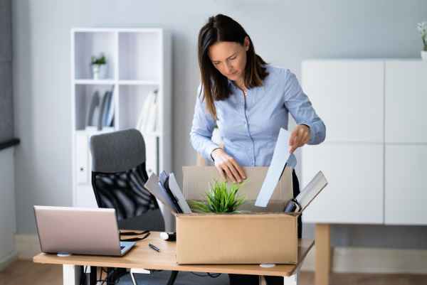 A woman packs her belongings into a box after being dismissed from her job