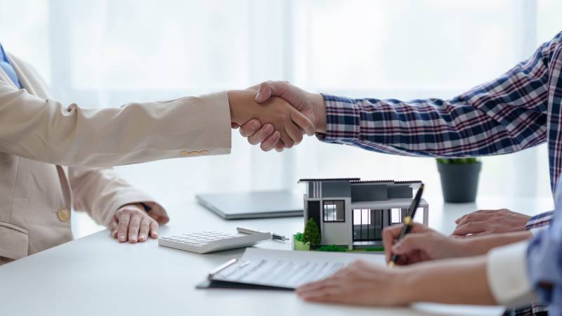 A client shakes the hand of a solicitor after purchasing a house