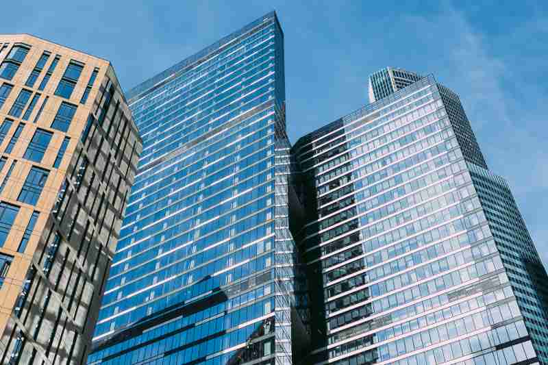 A view looking up at high-rise commercial office buildings, pictured on a sunny day