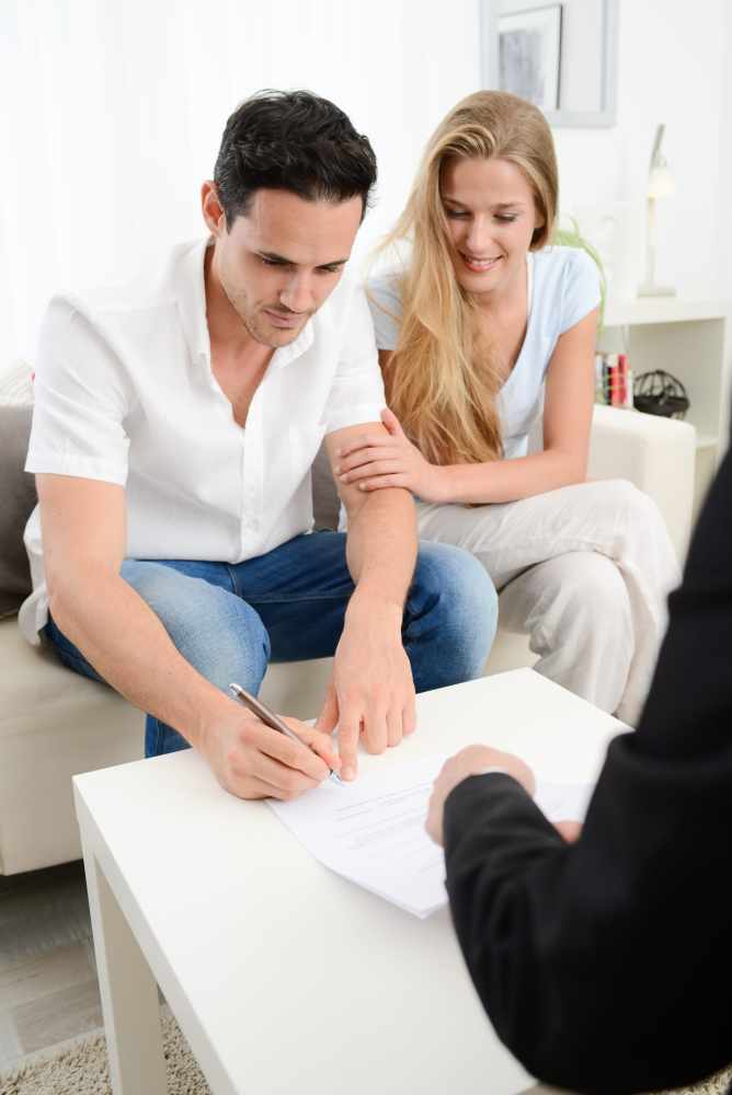 A young couple write their will during a consultation with a solicitor